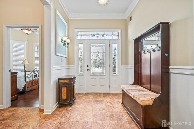 foyer featuring ornamental molding, ceiling fan, and a healthy amount of sunlight