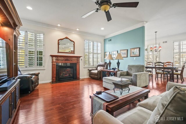 living room with ornamental molding, dark hardwood / wood-style flooring, and ceiling fan with notable chandelier