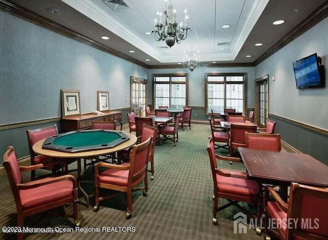 playroom with carpet flooring, french doors, ornamental molding, a tray ceiling, and a notable chandelier