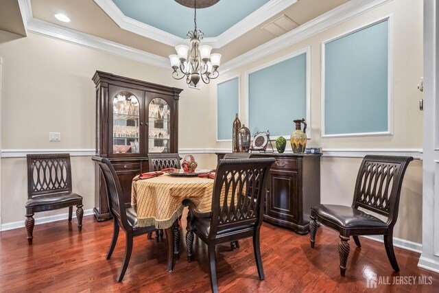 dining room featuring ornamental molding, an inviting chandelier, a raised ceiling, and wood-type flooring