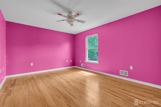 empty room with baseboards, visible vents, and wood finished floors