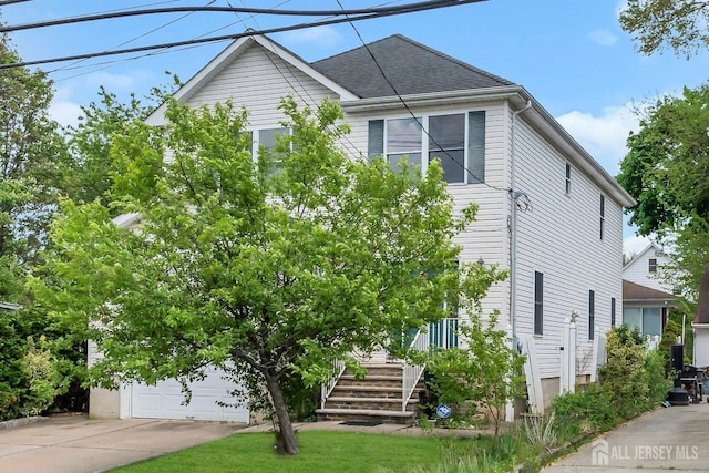 view of front of home featuring driveway, a shingled roof, and a garage