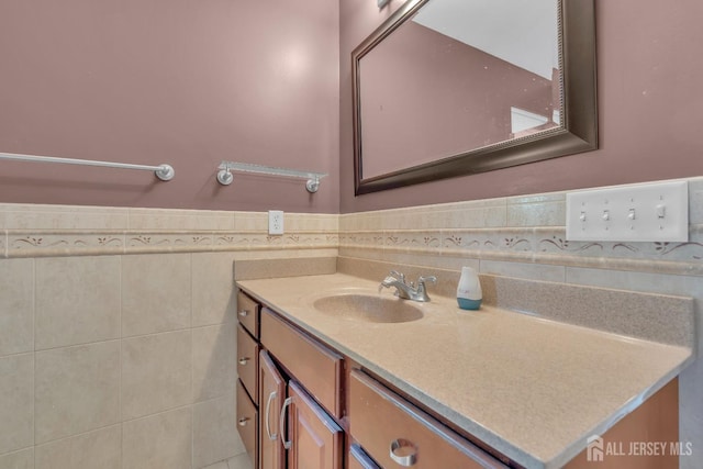 bathroom featuring vanity, a wainscoted wall, and tile walls