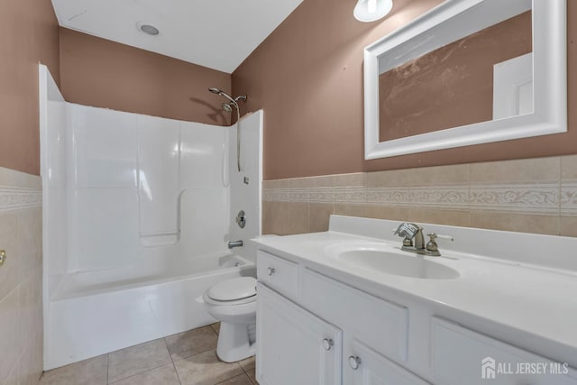 bathroom featuring vanity, toilet, tile walls, a wainscoted wall, and tile patterned floors