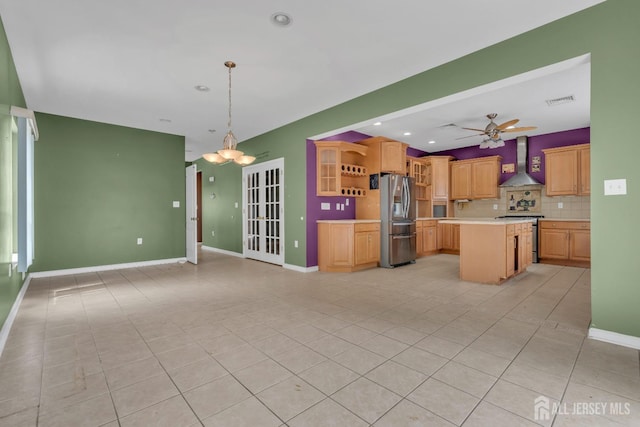 kitchen with decorative backsplash, light tile patterned flooring, wall chimney range hood, light countertops, and appliances with stainless steel finishes
