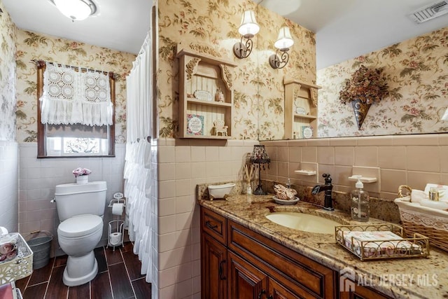 full bathroom with visible vents, wallpapered walls, wainscoting, tile walls, and toilet