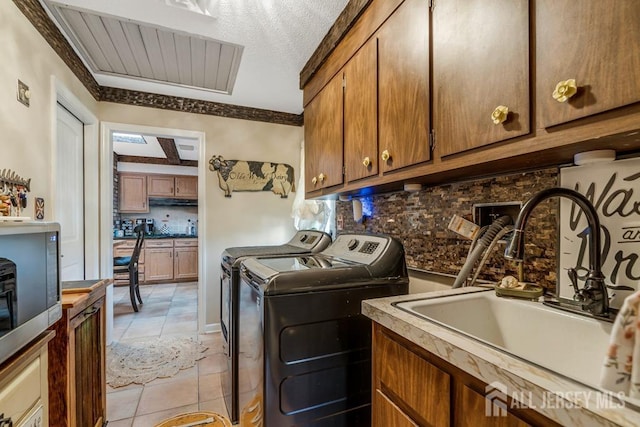 laundry room featuring a sink, light tile patterned floors, cabinet space, and washing machine and clothes dryer