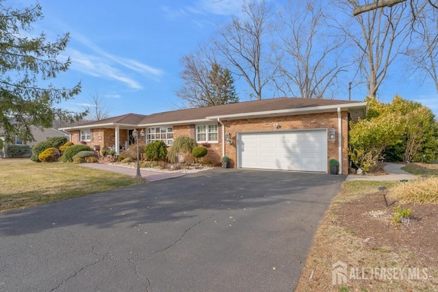 ranch-style home with brick siding, a front lawn, an attached garage, and driveway