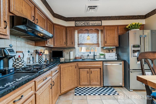 kitchen featuring visible vents, under cabinet range hood, a sink, backsplash, and stainless steel appliances