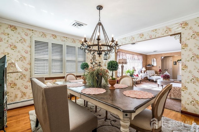 dining space with light wood finished floors, a notable chandelier, wallpapered walls, and ornamental molding