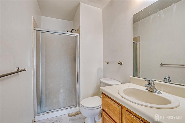 bathroom featuring toilet, vanity, and a shower with shower door