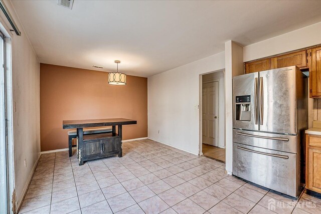 kitchen with stainless steel refrigerator with ice dispenser, light tile patterned flooring, and hanging light fixtures