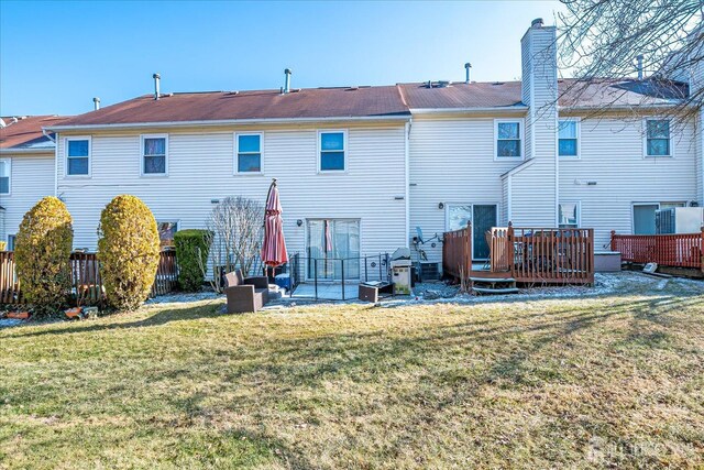 back of property featuring a lawn, a patio, and a wooden deck