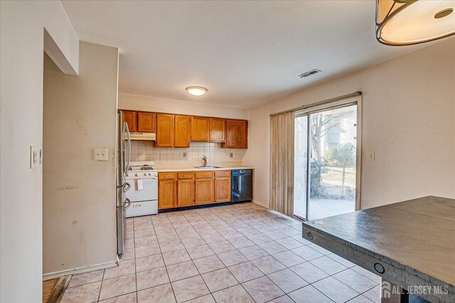 kitchen featuring backsplash, white gas range oven, sink, black dishwasher, and light tile patterned floors