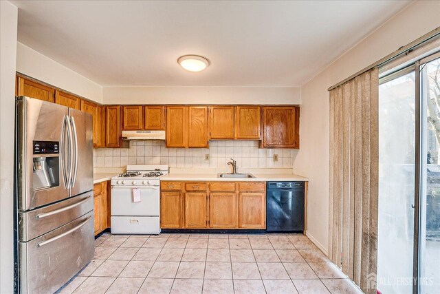 kitchen featuring white range with gas stovetop, stainless steel refrigerator with ice dispenser, light tile patterned flooring, dishwasher, and sink