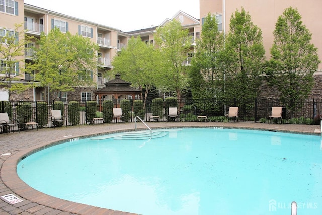 pool featuring fence and a gazebo
