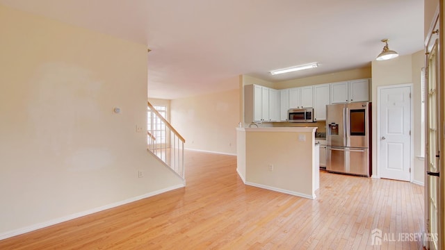 kitchen with light hardwood / wood-style flooring, stainless steel appliances, and white cabinets