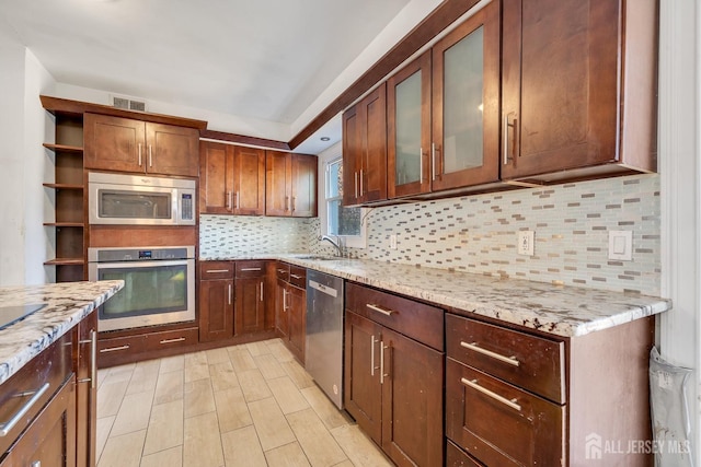 kitchen with stainless steel appliances, decorative backsplash, and light stone counters