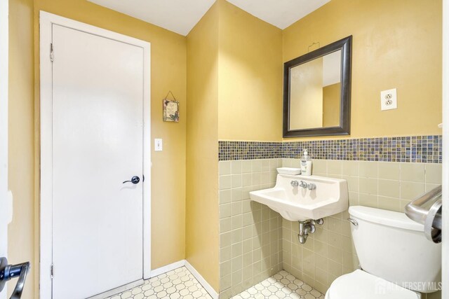 bathroom featuring tile walls, sink, and toilet