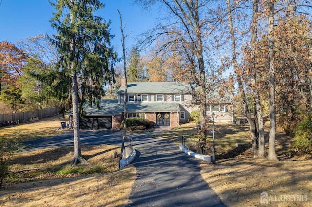 view of front facade featuring a chimney, aphalt driveway, fence, french doors, and brick siding