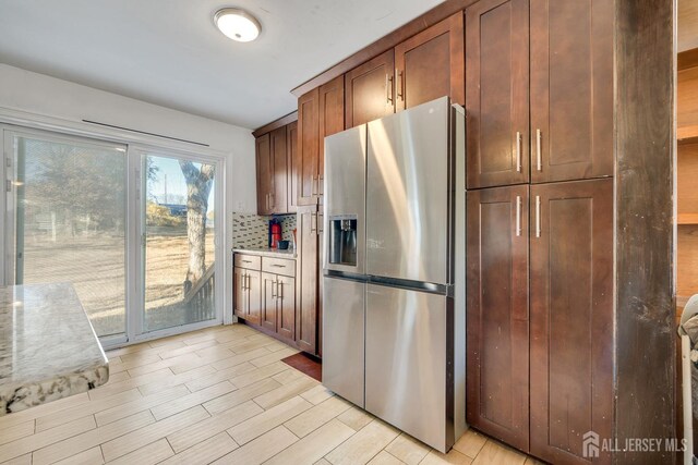 kitchen featuring tasteful backsplash, light hardwood / wood-style floors, and stainless steel fridge with ice dispenser