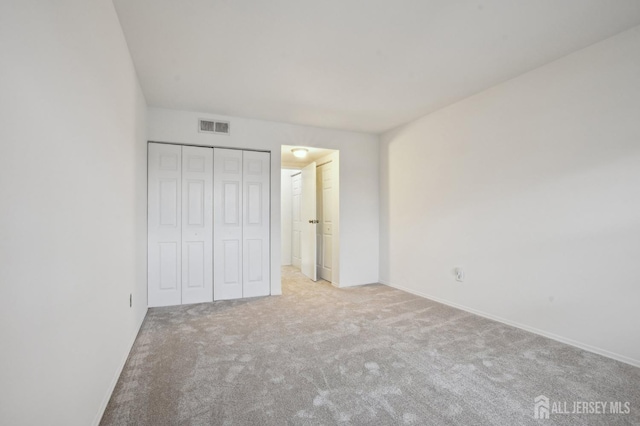 unfurnished bedroom with light colored carpet, a closet, visible vents, and baseboards