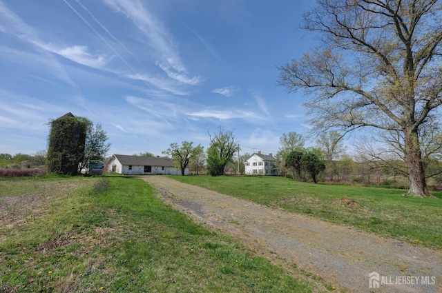 view of front facade with dirt driveway and a front yard
