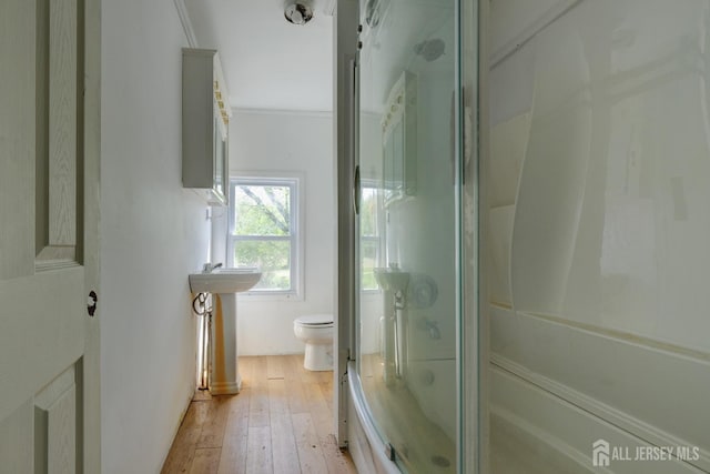 full bath featuring a shower with door, toilet, and hardwood / wood-style floors