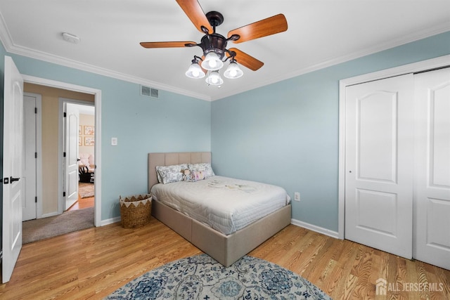 bedroom featuring wood finished floors, ornamental molding, baseboards, a ceiling fan, and a closet