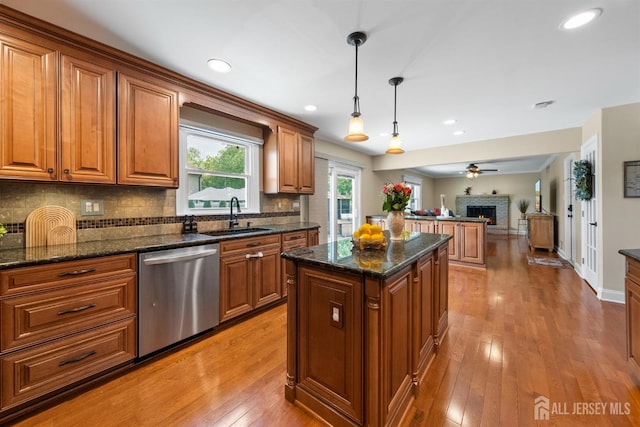 kitchen featuring dishwasher, a sink, brown cabinets, a kitchen island, and open floor plan