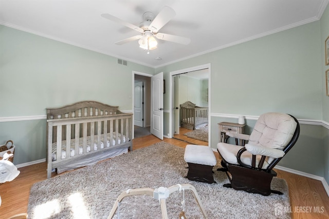 bedroom with wood finished floors, baseboards, crown molding, a ceiling fan, and a closet