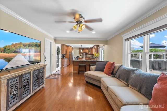 living room with ceiling fan, light wood-style floors, recessed lighting, crown molding, and baseboards