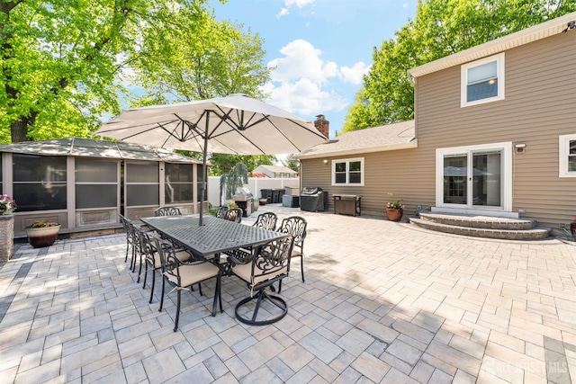 view of patio / terrace featuring a sunroom, outdoor dining area, and fence