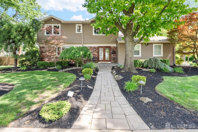 view of front of house with french doors, brick siding, and a front lawn