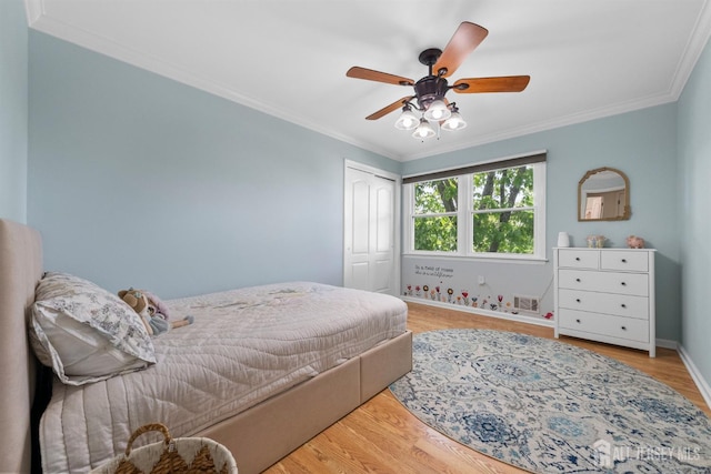 bedroom with crown molding, wood finished floors, a closet, ceiling fan, and baseboards