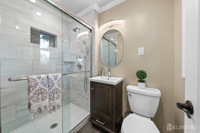 bathroom with ornamental molding, a shower stall, toilet, and vanity