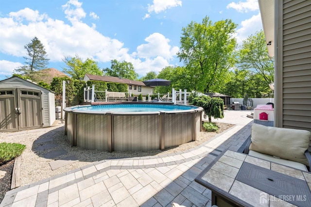 view of swimming pool featuring a storage unit, an outdoor structure, a patio, and fence