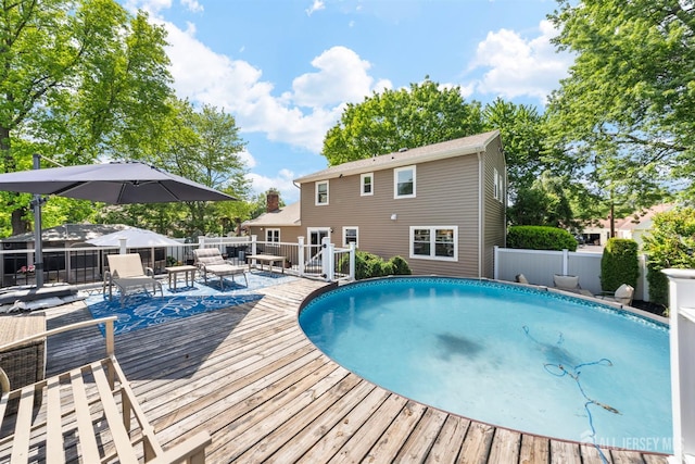 view of swimming pool featuring a deck and fence