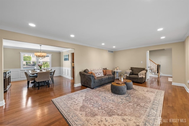 living room with stairs, wood finished floors, crown molding, recessed lighting, and a chandelier