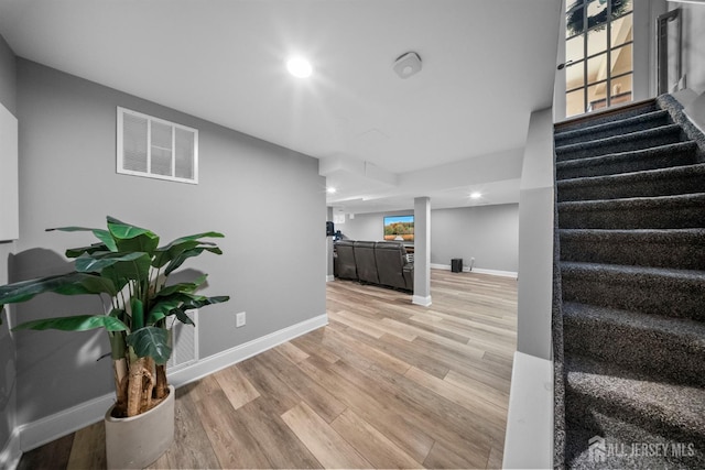 stairway with wood finished floors, baseboards, and recessed lighting