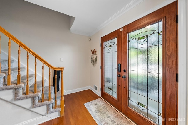 foyer entrance with stairway, baseboards, wood finished floors, and crown molding