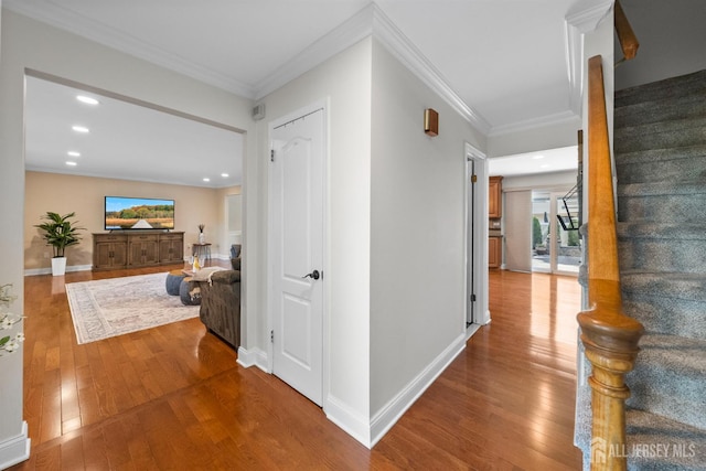 hall featuring stairs, wood-type flooring, recessed lighting, ornamental molding, and baseboards