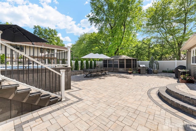 view of patio featuring a fenced backyard, a sunroom, stairs, outdoor dining space, and area for grilling