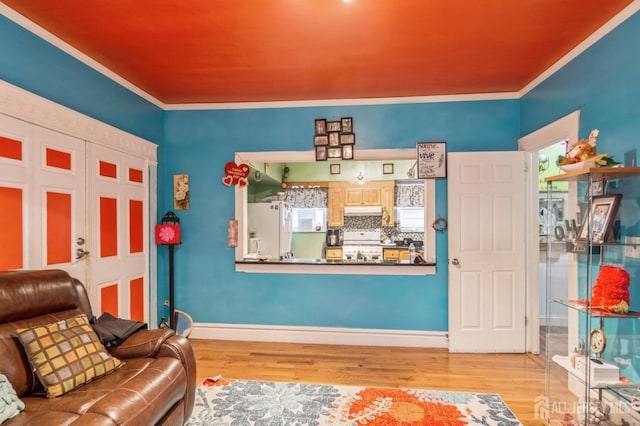 living area featuring light wood finished floors, baseboards, and ornamental molding