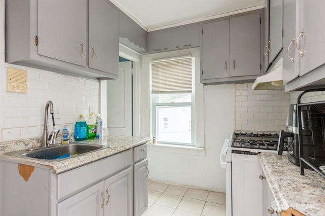 kitchen featuring gray cabinets, light countertops, white gas stove, under cabinet range hood, and a sink