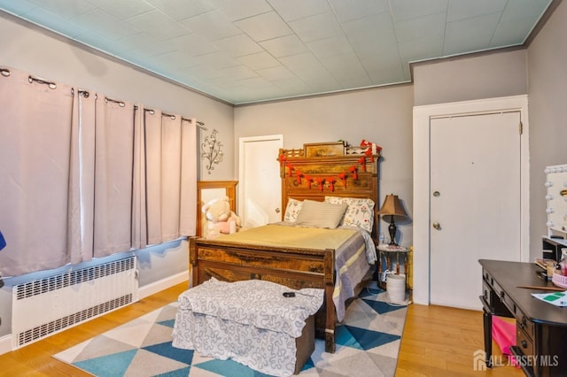 bedroom with light wood-style flooring and radiator