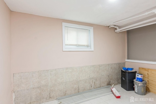 interior space with a wainscoted wall, tile walls, and tile patterned floors