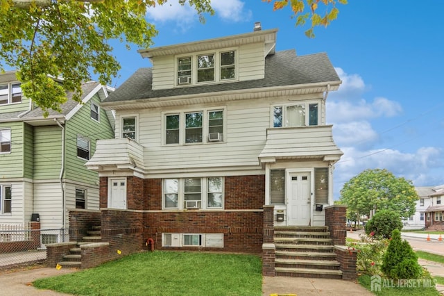 american foursquare style home featuring entry steps, roof with shingles, fence, a front lawn, and brick siding