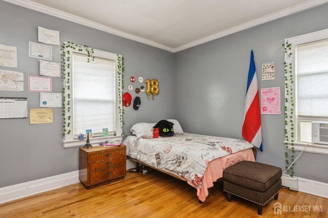 bedroom with ornamental molding, multiple windows, and light wood finished floors