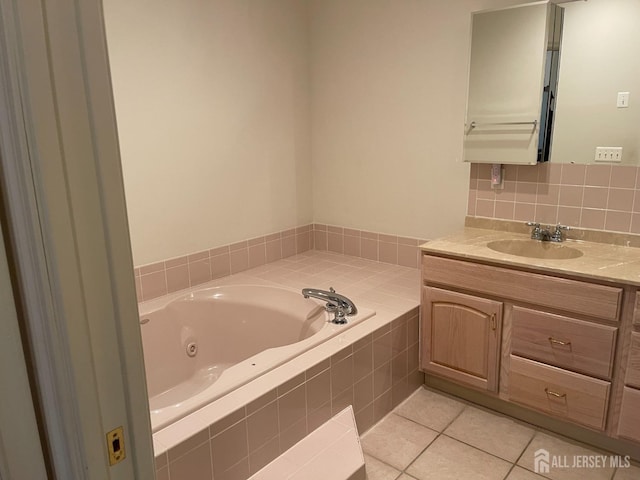 bathroom featuring tile patterned floors, a relaxing tiled tub, and vanity